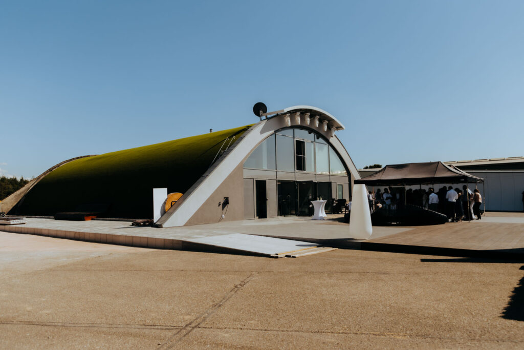 Event Hangar E210 am Baden Airpark von außen mit einem grünen Dach.